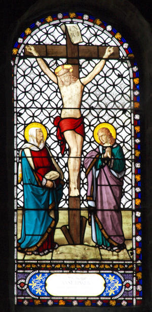 A stained glass window portraying the Crucifixion, with Mary and John at the foot of the cross