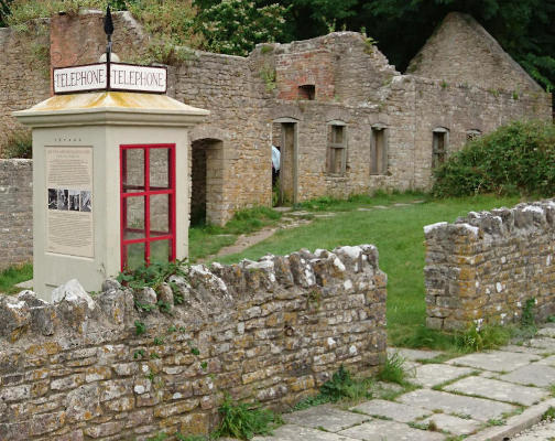 An old-fashioned concrete phone box standing amongst ruins