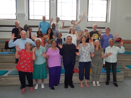 A large group of people of diverse ages and colours sing together
