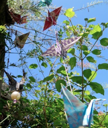 origami peace cranes in a tree against a blue sky