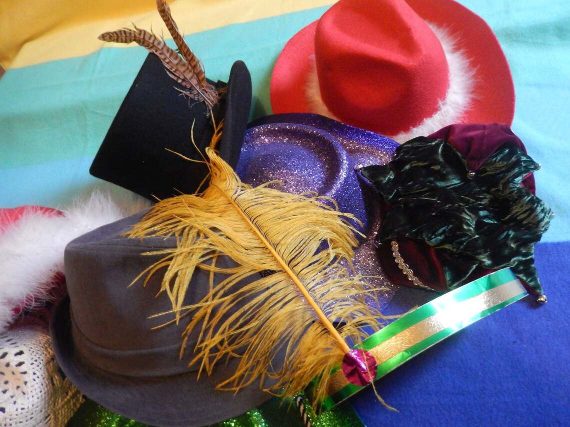 a collection of hats on a rainbow blanket 