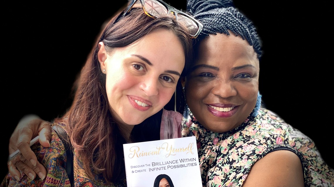 Image of two women embracing holding a book