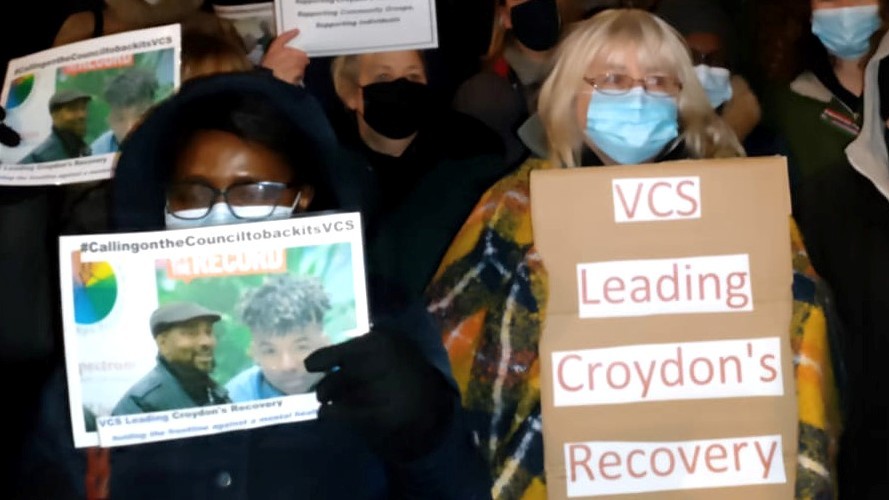 Photo of a lady holding a placard saying VCS leading the borough recovery