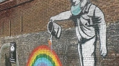 Photo of graffiti art showing a person with a watercan pouring into a rainbow