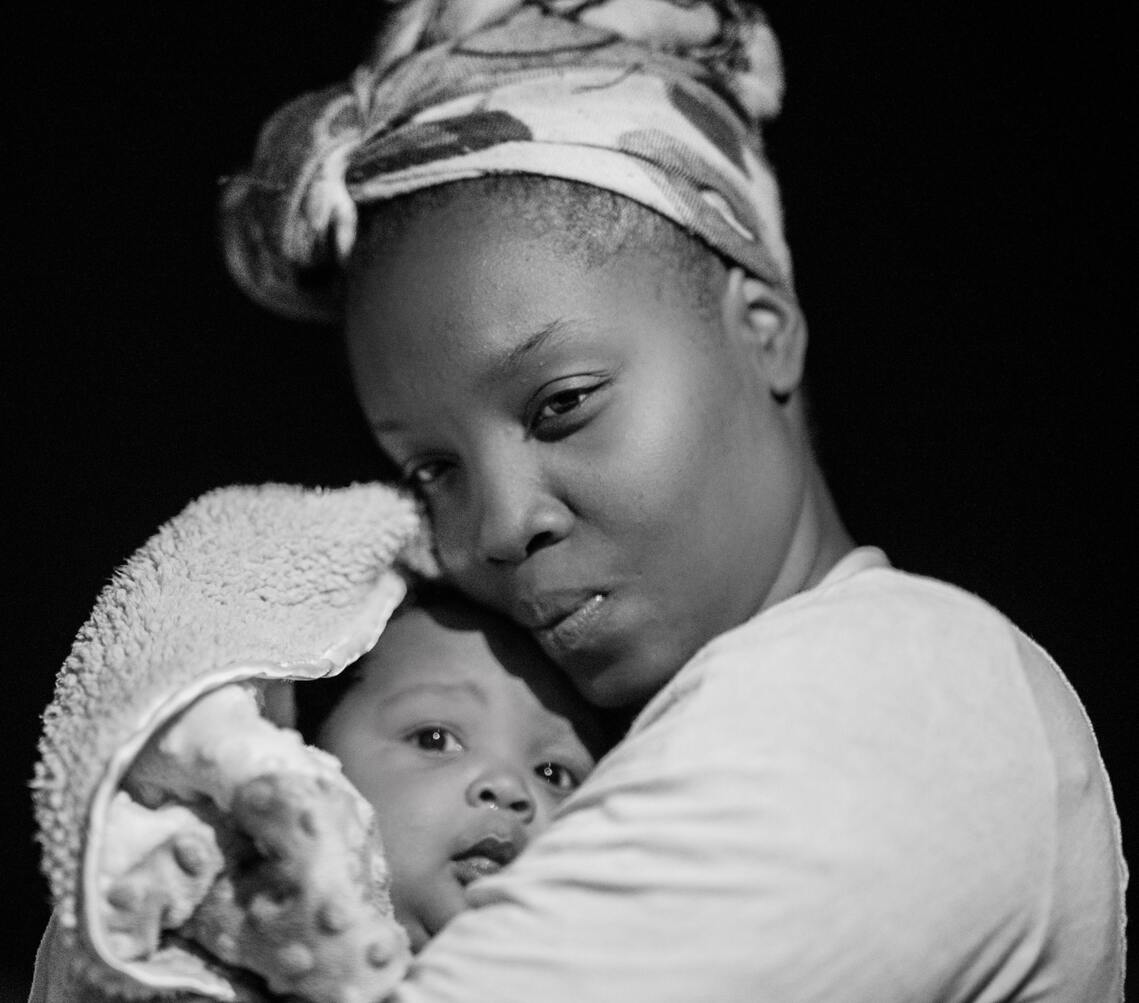 a yong mother holds her baby close to her bosom