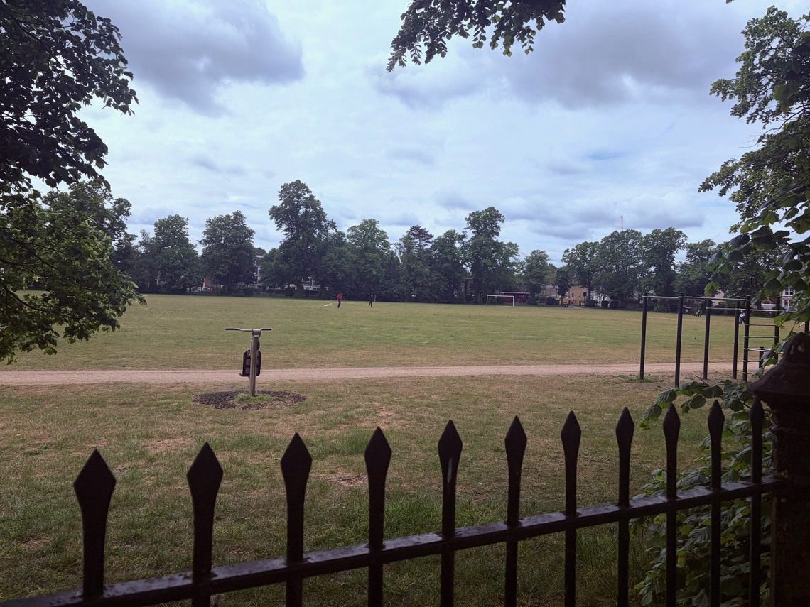 Looking over the railings at free outdoor gym equipment which is around the outside edges of the park