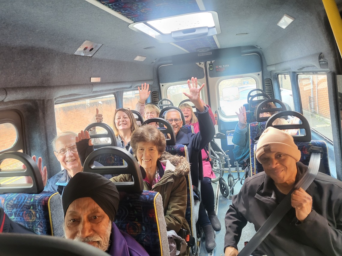 People in a minibus waving to the camera.