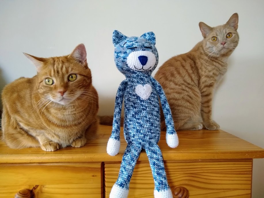 Two ginger cats and a toy cat sitting together