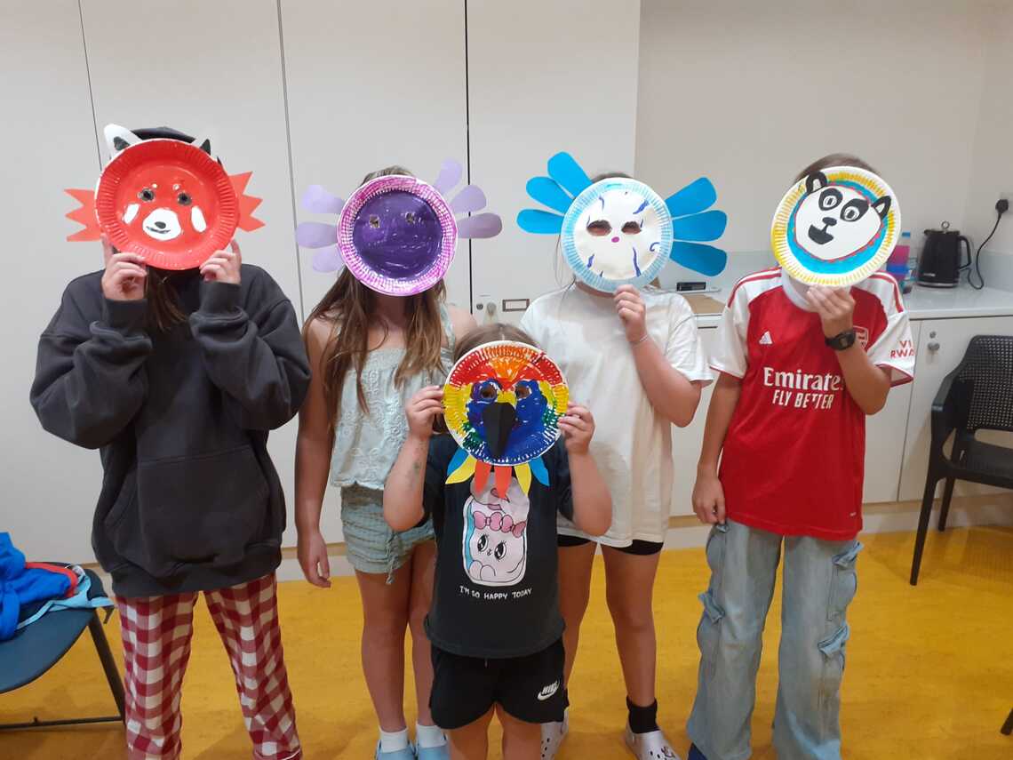 Five children holding masks of animals in front of their faces.