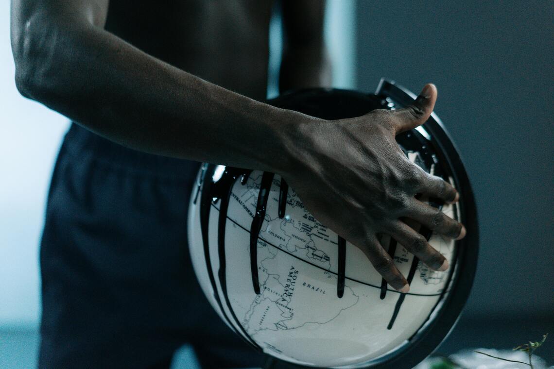 Globe dripping with Oil, held by a man of colour