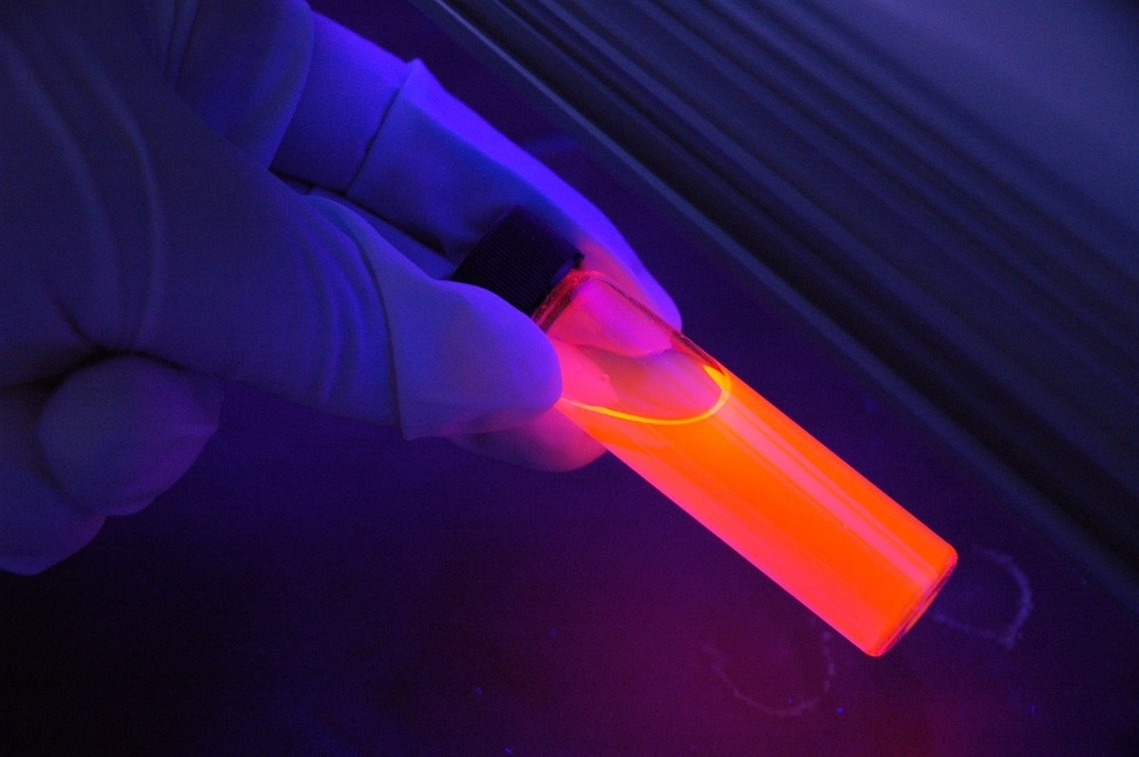 A test tube held by a gloved hand